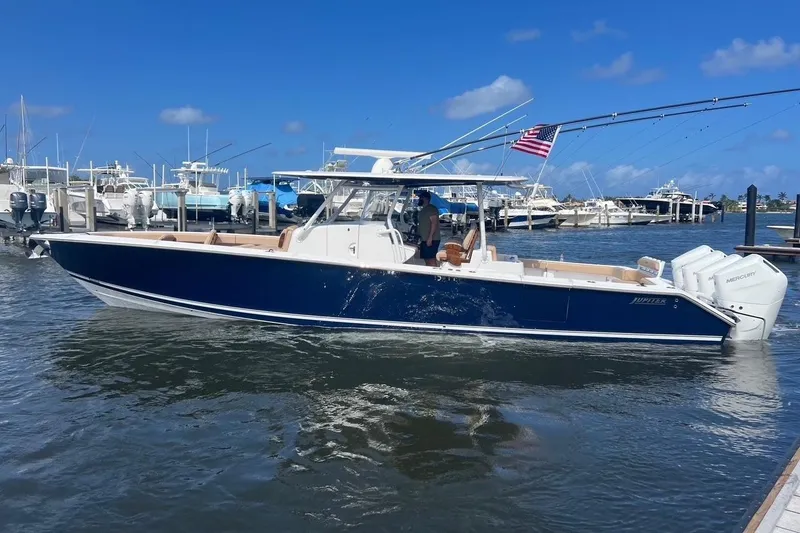 The Image of 2024 Jupiter 43 boat with triple Mercury engines docked in a marina. - 0