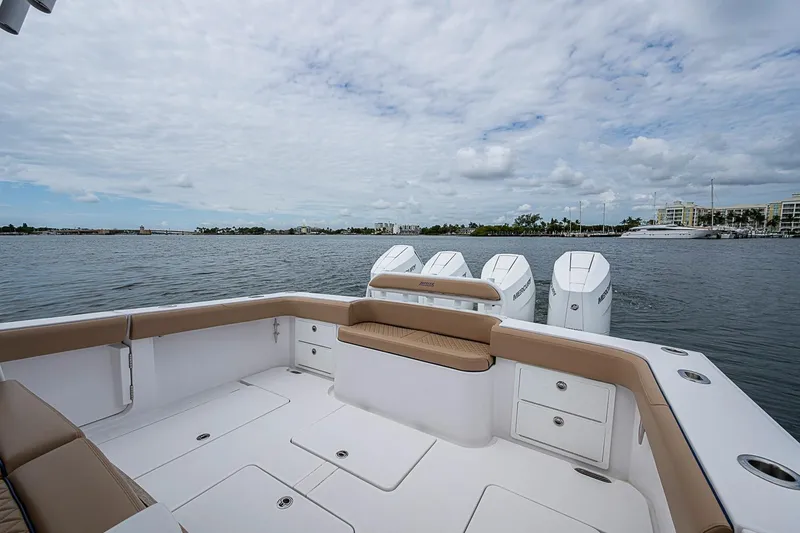 Slide: The Image of 2024 Jupiter 43 boat deck with seating and multiple outboard engines on a calm waterway. - 26