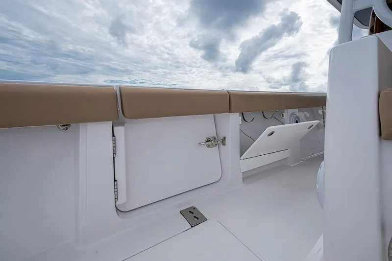 Slide: The Image of 2024 Jupiter 43 boat interior with storage compartments and cushioned seating under cloudy sky. - 31