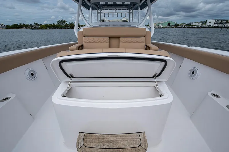 Slide: The Image of 2024 Jupiter 43 boat with open storage compartment, beige seating, and scenic water backdrop. - 39