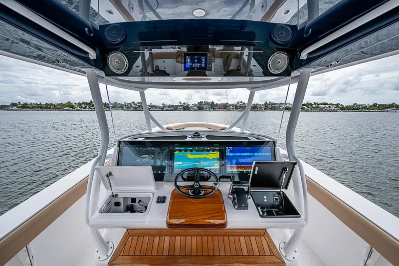 Slide: The Image of Helm of 2024 Jupiter 43 boat with advanced navigation displays on a calm waterway. - 46