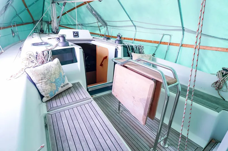 Slide: The Image of 2019 Hanse 315 sailboat cockpit with wooden flooring and nautical decor under a green canopy. - 22