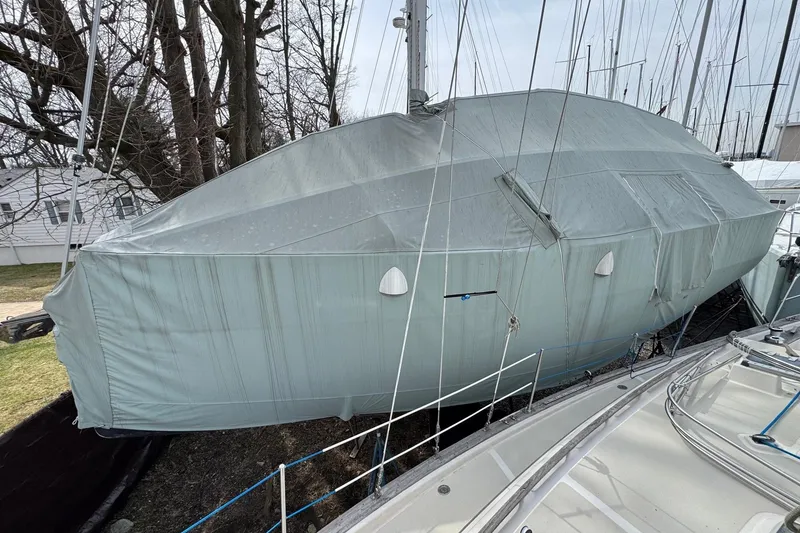 Slide: The Image of Covered 2019 Hanse 315 sailboat in storage, surrounded by trees and other boats. - 30