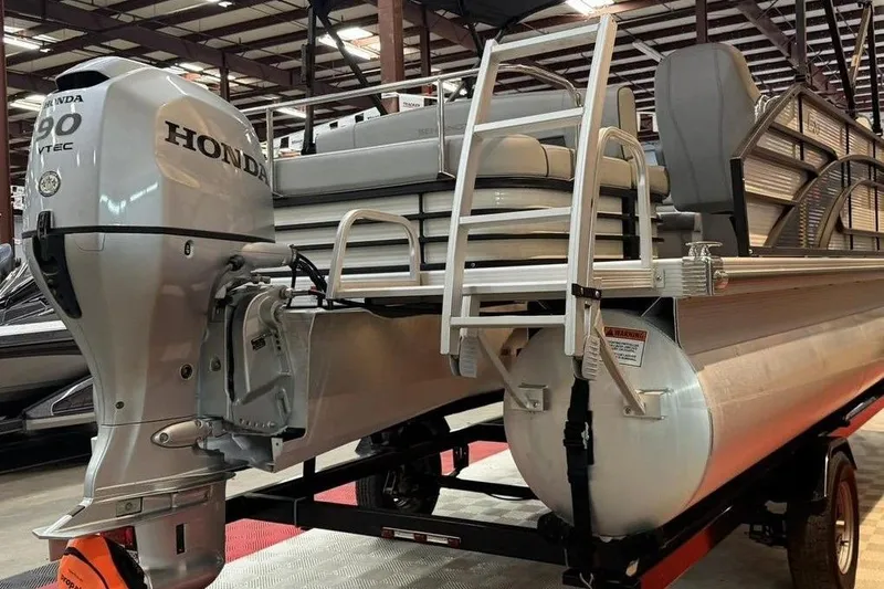 Slide: The Image of 2021 Bennington 20 LSB pontoon boat with Honda outboard motor in showroom. - 2