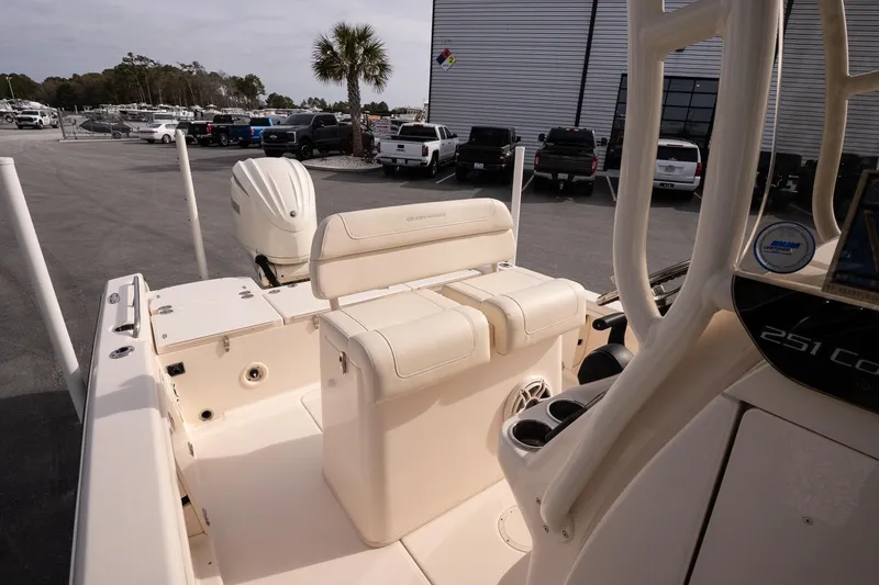 Slide: The Image of 2024 Grady-White 251 Coastal Explorer boat interior with seating and motor, parked outdoors. - 22