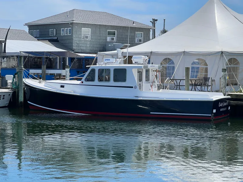 The Image of 2022 Wesmac 38 boat docked near waterfront buildings and a white tent. - 0