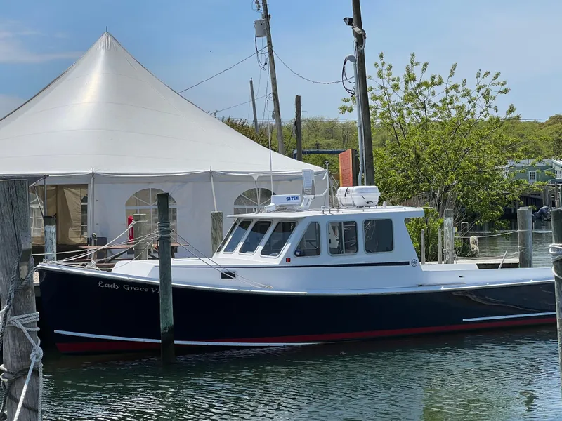 Slide: The Image of 2022 Wesmac 38 boat docked near a white tent and trees. - 2