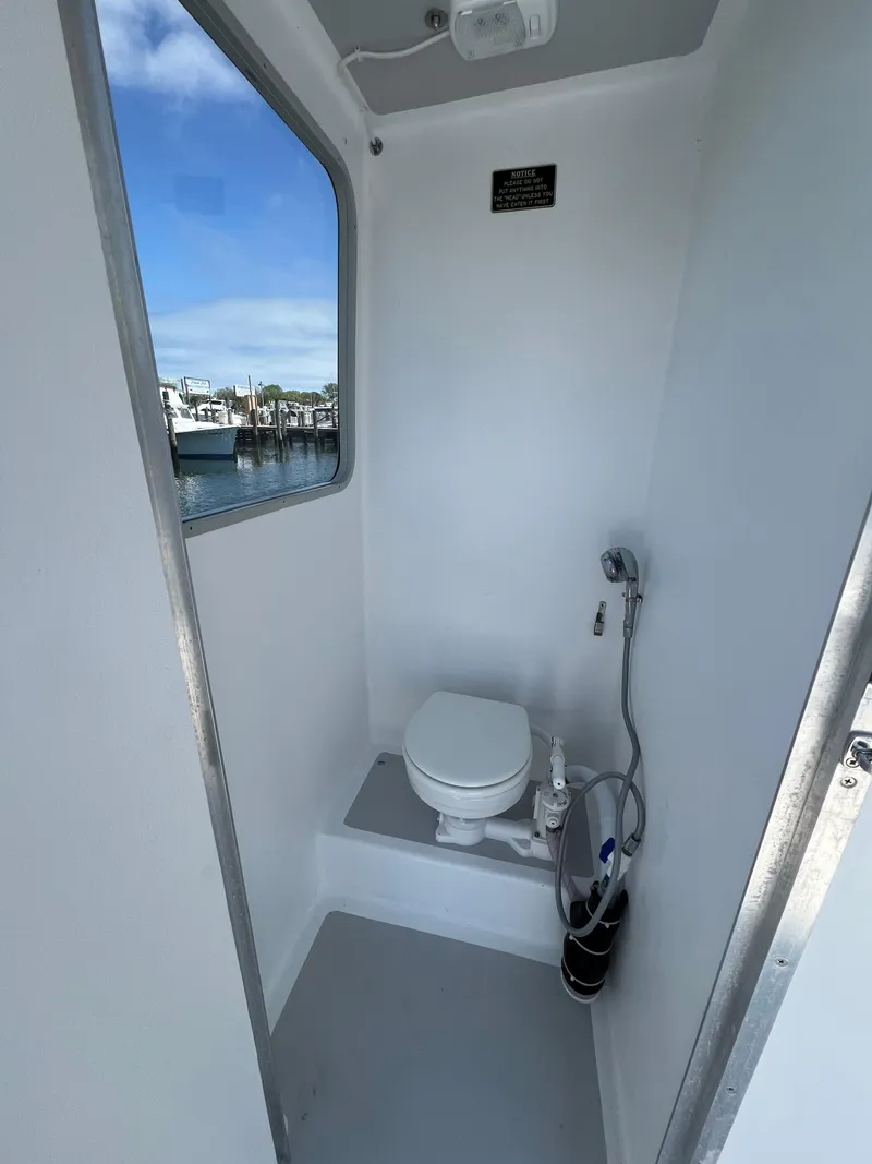 Slide: The Image of 2022 Wesmac 38 boat interior bathroom with toilet and showerhead, featuring a window view. - 36