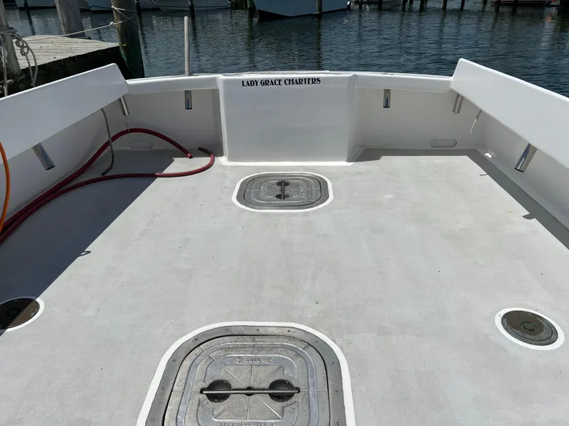 Slide: The Image of Open deck of 2022 Wesmac 38 boat at dock, featuring storage hatches and "Lady Grace Charters" signage. - 4