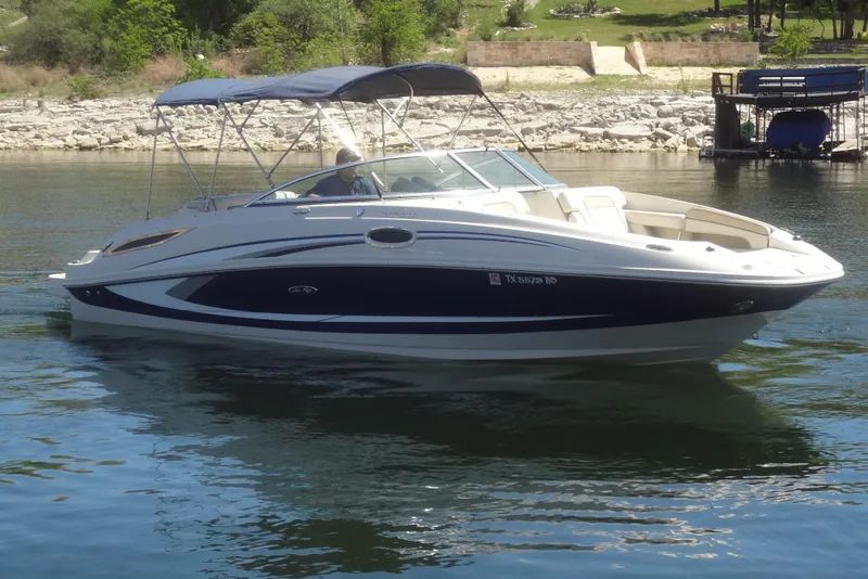 The Image of 2010 Sea Ray 260 Sundeck boat on calm water, featuring a sleek design and canopy. - 0