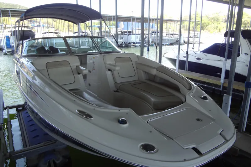 Slide: The Image of 2010 Sea Ray 260 Sundeck boat docked in a marina, featuring spacious seating and canopy. - 12
