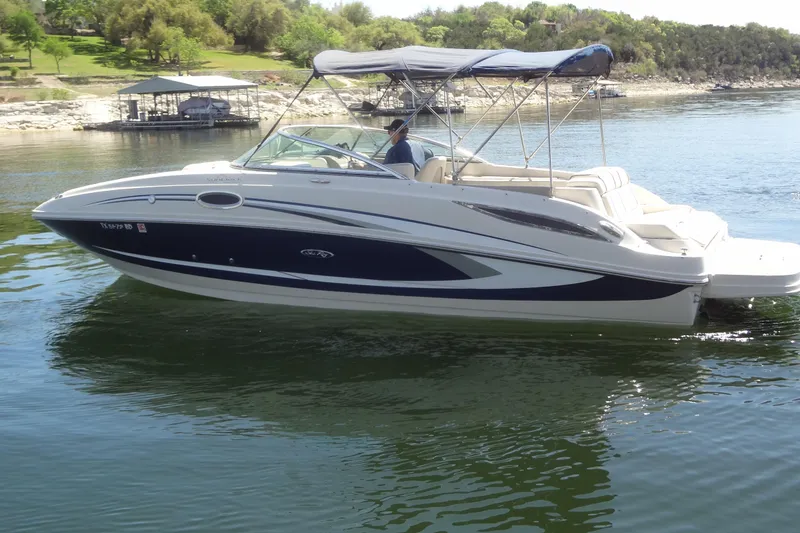 Slide: The Image of 2010 Sea Ray 260 Sundeck boat cruising on a calm lake with lush green shoreline. - 5