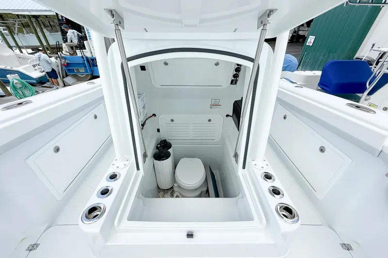 Slide: The Image of 2024 Yellowfin 34 Offshore boat interior with a compact marine toilet and storage space. - 11