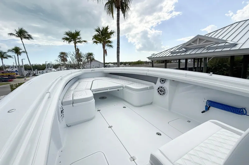 Slide: The Image of 2024 Yellowfin 34 Offshore boat deck with seating, palm trees, and marina backdrop. - 21