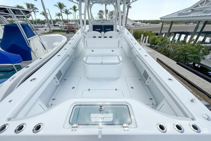 Slide: The Image of 2024 Yellowfin 34 Offshore boat interior with seating and storage, docked near palm trees. - 24