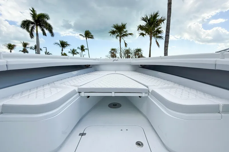 Slide: The Image of 2024 Yellowfin 34 Offshore boat interior with white seating and palm trees in the background. - 8