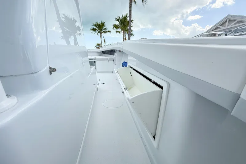 Slide: The Image of 2024 Yellowfin 34 Offshore boat deck with open storage compartment, palm trees in background. - 6