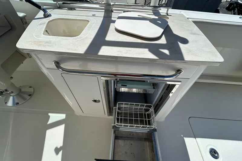 Slide: The Image of 2018 Boston Whaler 270 Vantage boat sink and storage area with cutting board. - 12