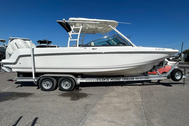 Slide: The Image of 2018 Boston Whaler 270 Vantage boat on trailer, parked outdoors under clear sky. - 2