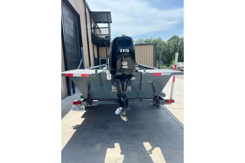 Slide: The Image of 1999 Aluminum Boat with outboard motor, parked on a trailer near a building. - 5