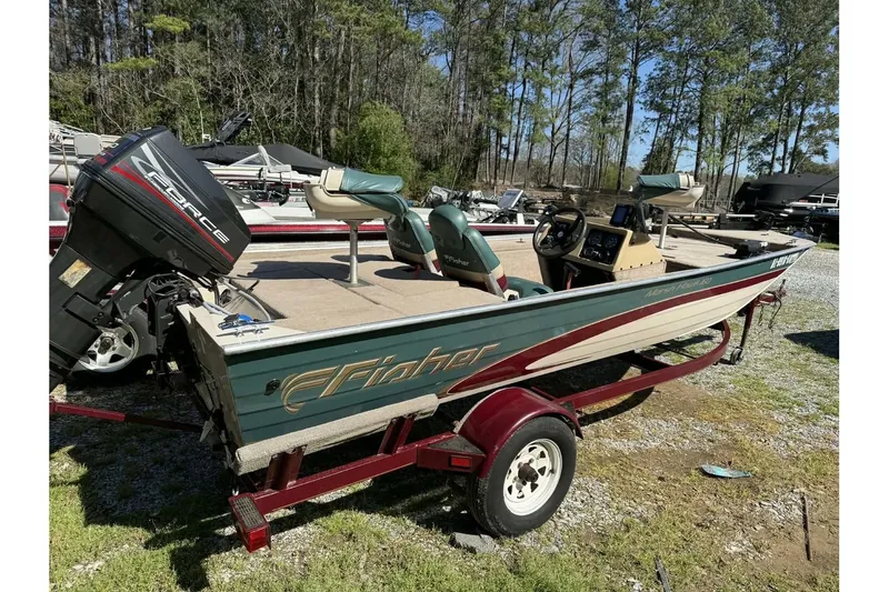 Slide: The Image of 1997 Fisher 1600 boat on trailer with outboard motor, parked outdoors. - 13