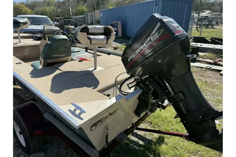 Slide: The Image of 1997 Fisher 1600 boat with Force outboard motor, parked outdoors. - 6