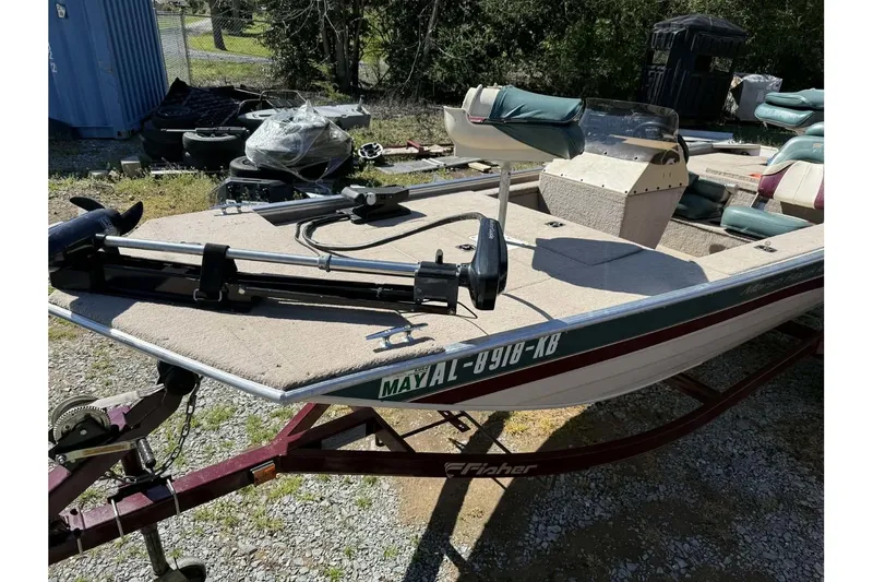 Slide: The Image of 1997 Fisher 1600 boat on trailer, equipped with trolling motor and seating, parked outdoors. - 7