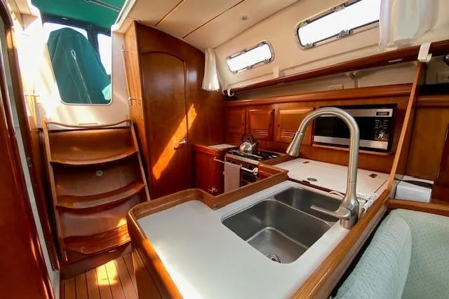 Slide: The Image of Interior of 2005 Beneteau Oceanis 373 sailboat with wooden cabinetry and modern kitchen amenities. - 10