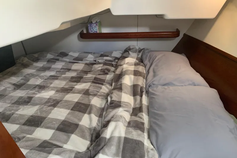 Slide: The Image of Cozy cabin bed in a 2005 Beneteau Oceanis 373 sailboat, featuring plaid bedding and pillows. - 25