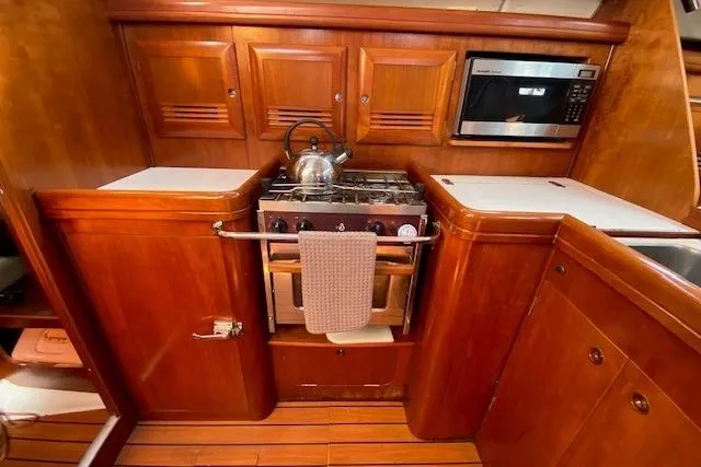 Slide: The Image of 2005 Beneteau Oceanis 373 yacht kitchen with wooden cabinets and modern appliances. - 9