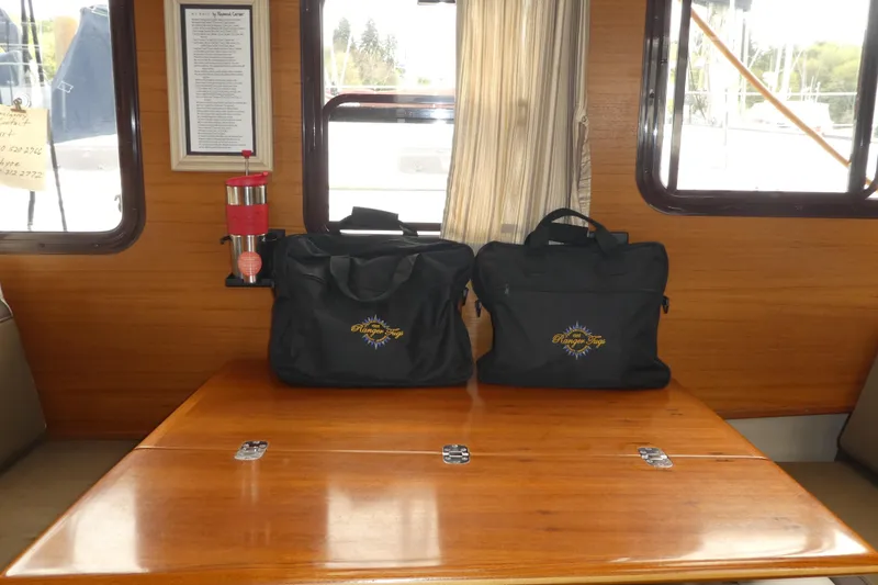 Slide: The Image of Interior of 2015 Ranger Tugs R-25 SC with branded bags on wooden table. - 11