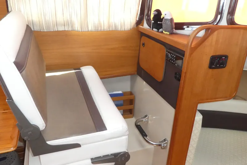 Slide: The Image of Interior of 2015 Ranger Tugs R-25 SC boat with helm seat and wooden paneling. - 12