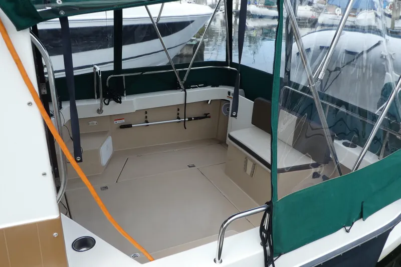 Slide: The Image of 2015 Ranger Tugs R-25 SC boat interior with green canopy and seating area. - 2