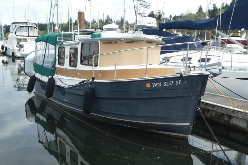 Slide: The Image of 2015 Ranger Tugs R-25 SC boat docked in a marina, featuring a blue hull and green canopy. - 25