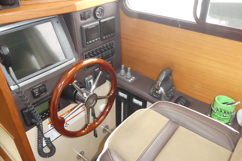 Slide: The Image of 2015 Ranger Tugs R-25 SC helm with steering wheel, navigation controls, and wood paneling. - 5