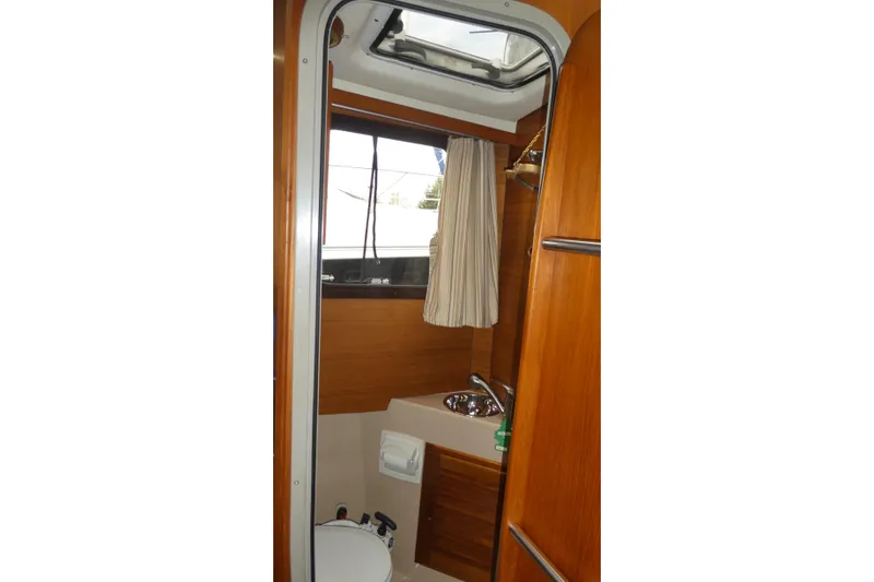 Slide: The Image of 2015 Ranger Tugs R-25 SC boat bathroom with wood finish and compact design. - 7