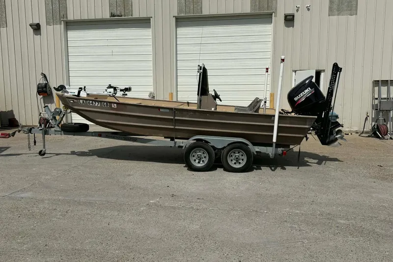 Slide: The Image of 2014 Southfork 1860 boat on trailer with Suzuki outboard motor, parked outside a building. - 3