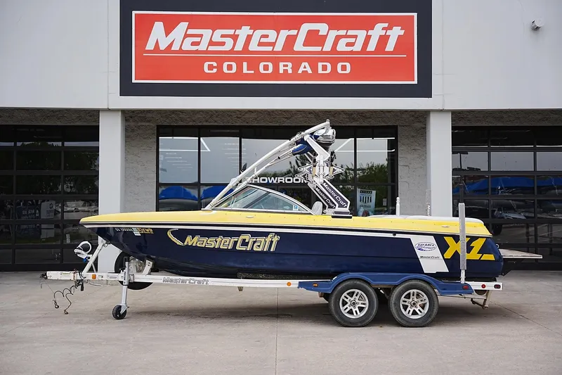 The Image of 2007 MasterCraft X10 boat on trailer at dealership, MasterCraft Colorado sign above. - 1