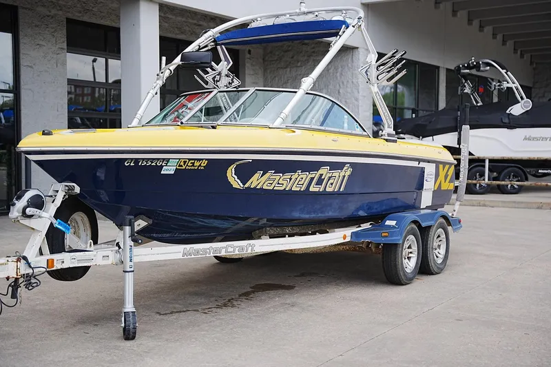 Slide: The Image of 2007 MasterCraft X10 boat on trailer, blue and yellow design, parked outdoors. - 6