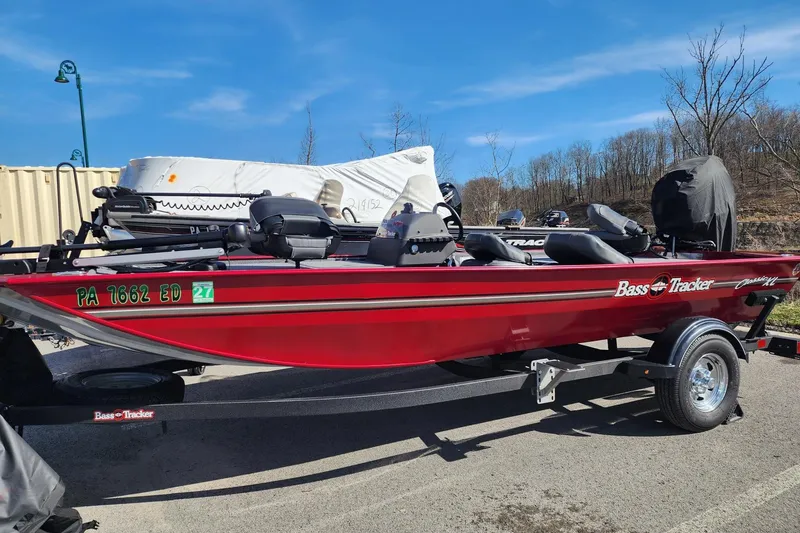 The Image of 2024 Tracker Bass Tracker Classic XL boat in vibrant red on a trailer, parked outdoors. - 0