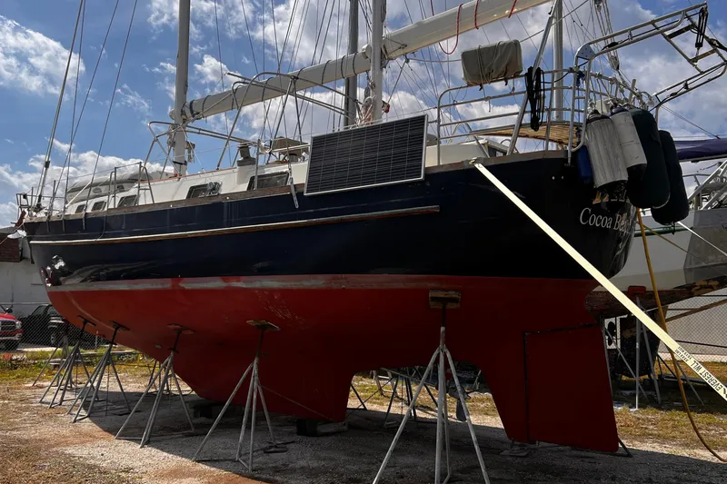 Slide: The Image of 1980 Morgan 462 sailboat on stands, featuring a red hull and solar panel. - 24