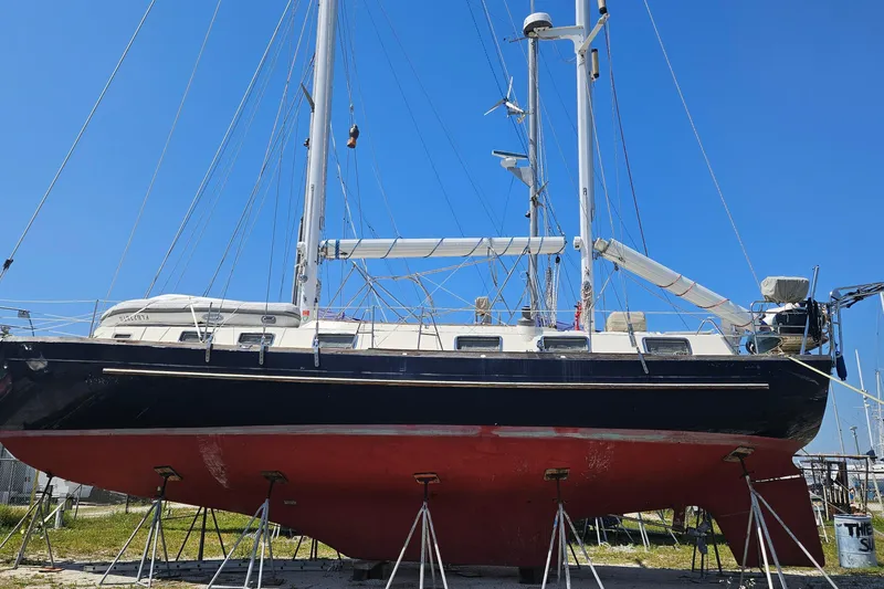 Slide: The Image of 1980 Morgan 462 sailboat on stands, blue hull, red bottom, clear sky background. - 25