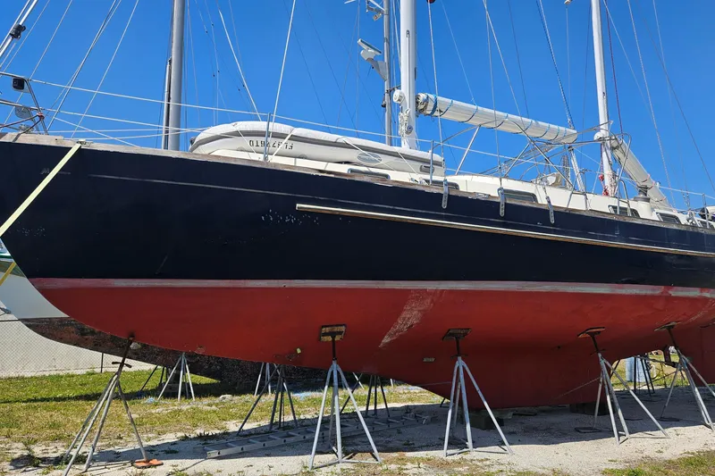 Slide: The Image of 1980 Morgan 462 sailboat on stands, black hull, red bottom, clear blue sky background. - 26