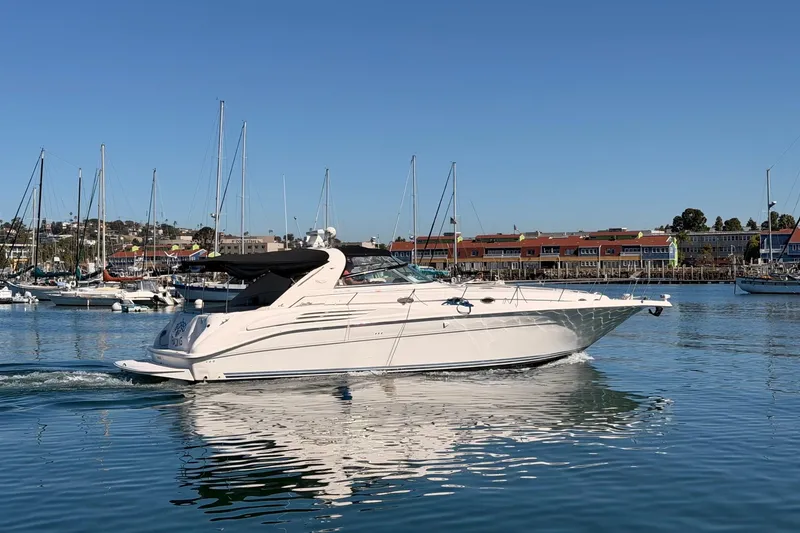 Slide: The Image of 1996 Sea Ray 450 Sundancer yacht cruising in a marina with sailboats and buildings in the background. - 1