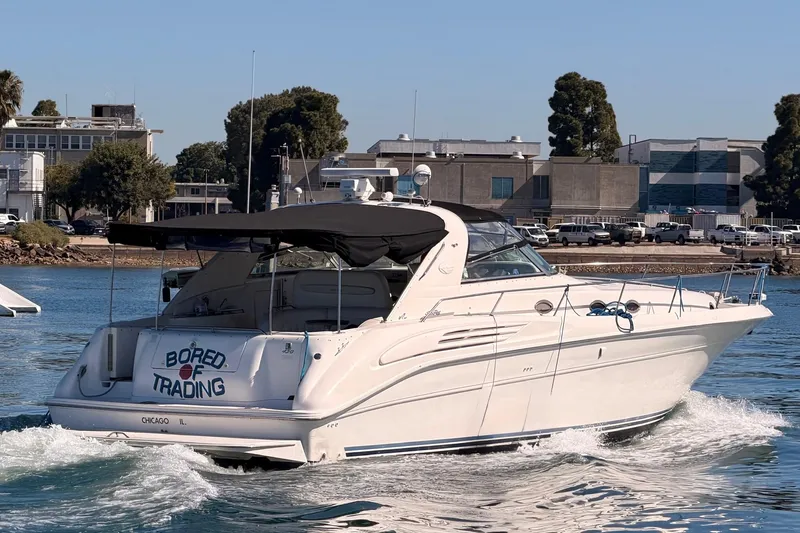 Slide: The Image of 1996 Sea Ray 450 Sundancer yacht cruising near an industrial waterfront. - 2