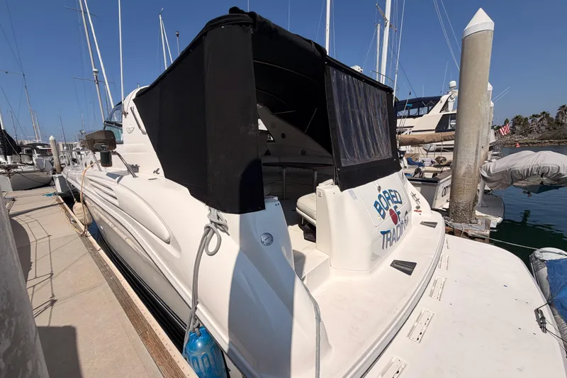 Slide: The Image of 1996 Sea Ray 450 Sundancer yacht docked at marina, featuring black canopy and sleek design. - 7