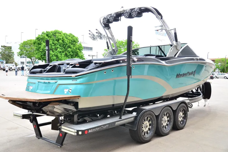 Slide: The Image of 2017 MasterCraft X26 boat on trailer, turquoise and silver design, parked outdoors. - 3