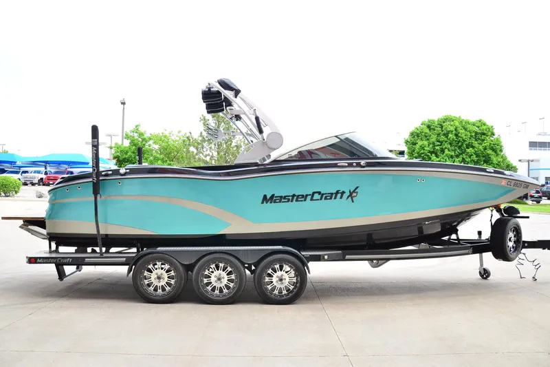 Slide: The Image of 2017 MasterCraft X26 boat on trailer, turquoise and black design, parked outdoors. - 4