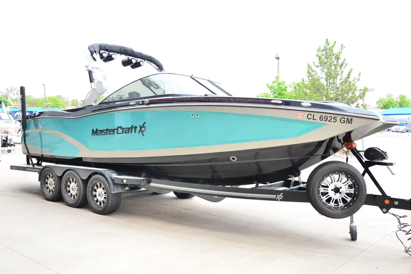 Slide: The Image of 2017 MasterCraft X26 boat on trailer, turquoise and black design, parked outdoors. - 5