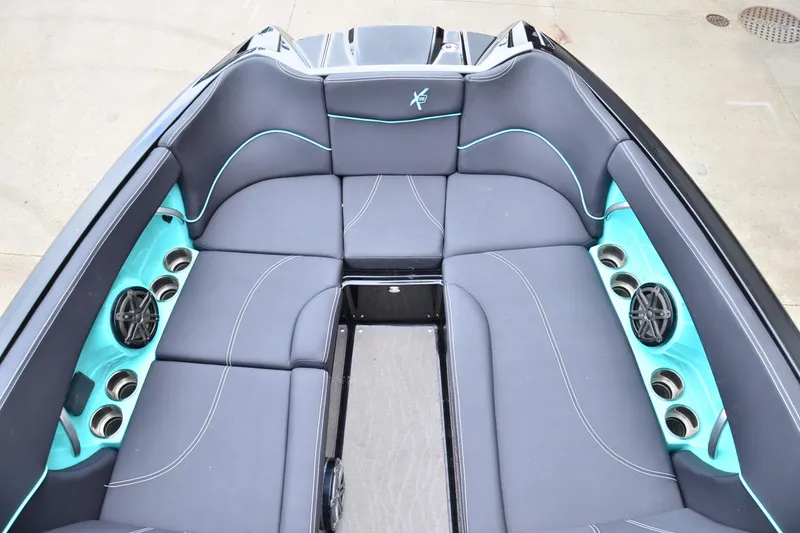 Slide: The Image of 2017 MasterCraft X26 boat interior with gray and teal seating, cup holders, and speakers. - 7